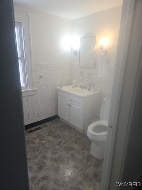 75 Schaefer Rd, West Seneca, NY 14218 - bathroom featuring toilet, vanity, visible vents, and tile walls