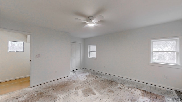 unfurnished bedroom with multiple windows, ceiling fan, a closet, and light hardwood / wood-style floors