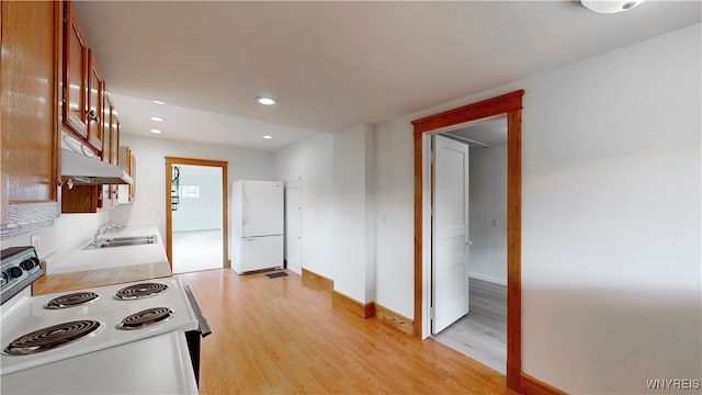 kitchen featuring white appliances, light hardwood / wood-style floors, and sink