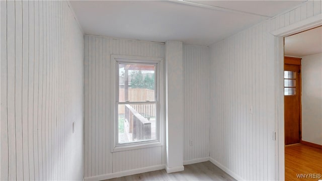 spare room featuring wooden walls and light hardwood / wood-style flooring