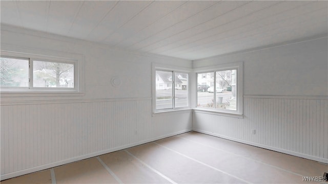 unfurnished room with wood walls, a healthy amount of sunlight, and wood ceiling