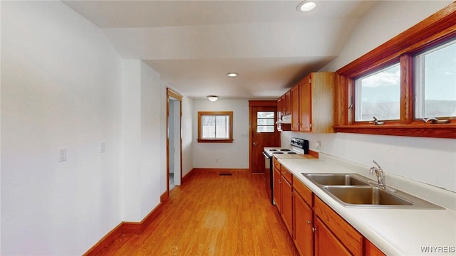 kitchen featuring brown cabinets, light wood-style flooring, a sink, white range with electric stovetop, and light countertops