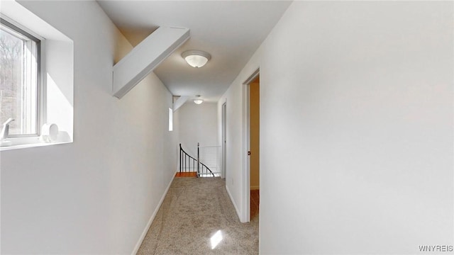 hallway featuring baseboards, an upstairs landing, and carpet flooring