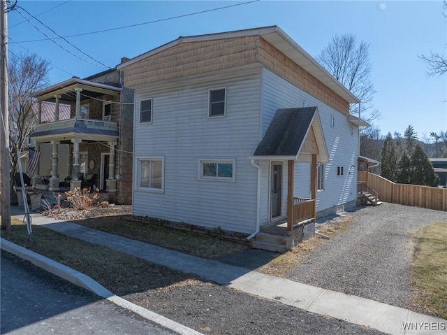 view of front of property with a balcony, driveway, and fence