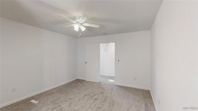 carpeted spare room with visible vents, baseboards, and ceiling fan