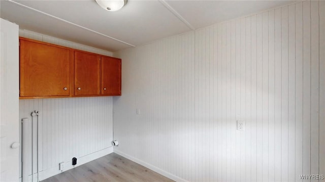 washroom with cabinet space, baseboards, and light wood finished floors