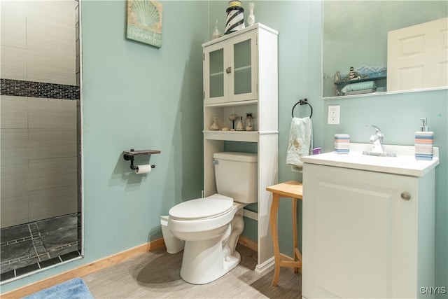 bathroom with tiled shower, vanity, and toilet