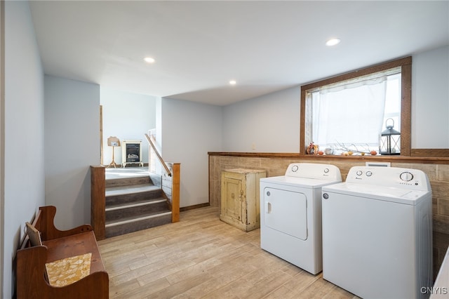 clothes washing area with light hardwood / wood-style floors and washing machine and clothes dryer