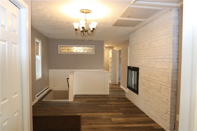 corridor with dark hardwood / wood-style flooring, baseboard heating, a textured ceiling, and a chandelier