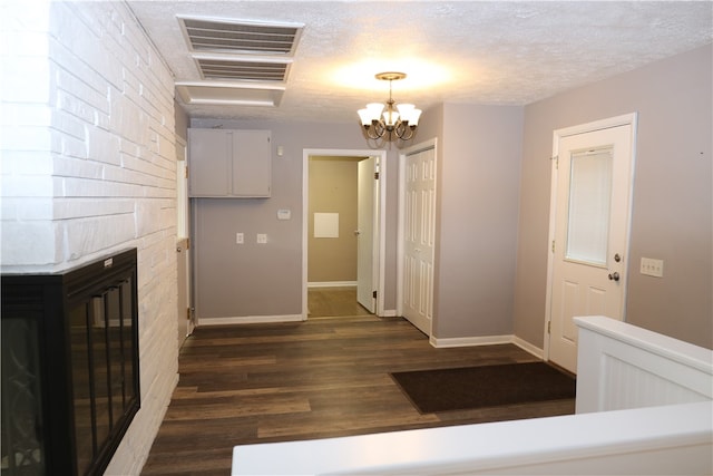 interior space featuring a textured ceiling, an inviting chandelier, and dark wood-type flooring