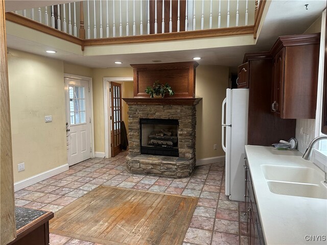 kitchen with white fridge, a stone fireplace, and sink