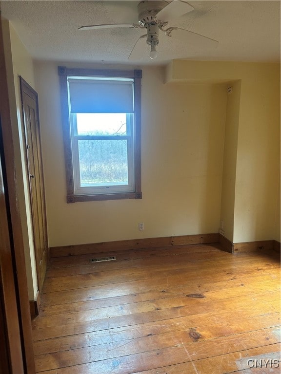 unfurnished room with a textured ceiling, light hardwood / wood-style flooring, and ceiling fan