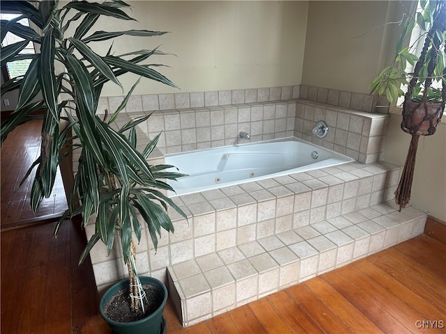 bathroom with wood-type flooring and a relaxing tiled tub