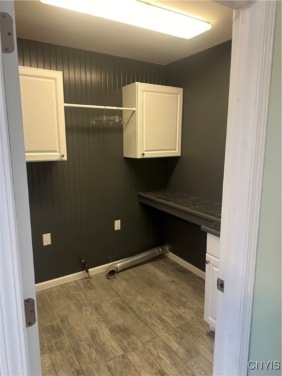 clothes washing area featuring cabinets, hardwood / wood-style floors, gas dryer hookup, and wooden walls