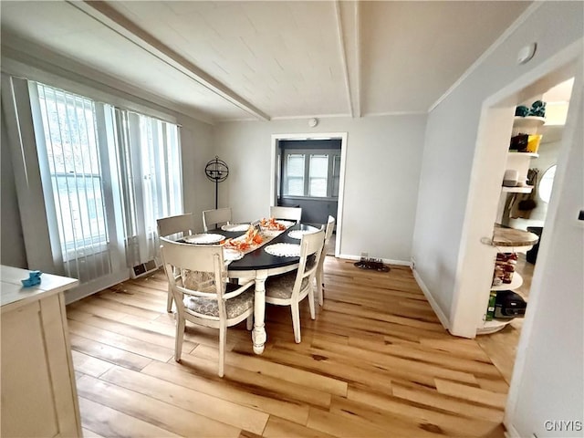 dining space with beam ceiling and light wood-type flooring