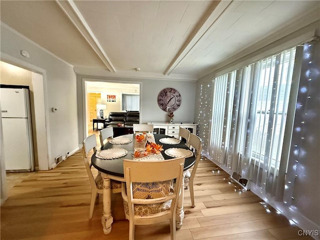 dining area with beamed ceiling, plenty of natural light, and light wood-type flooring