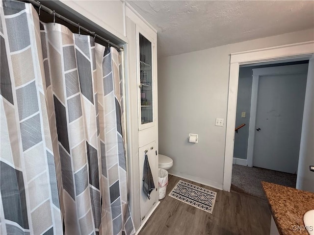 bathroom featuring hardwood / wood-style flooring, vanity, toilet, and a textured ceiling