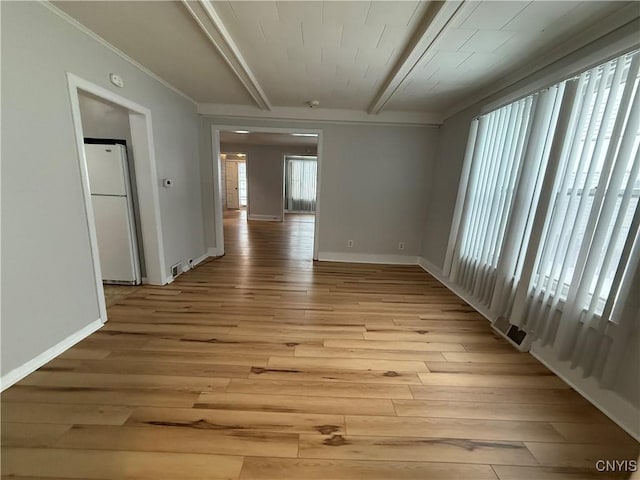 spare room with beamed ceiling, ornamental molding, and light wood-type flooring