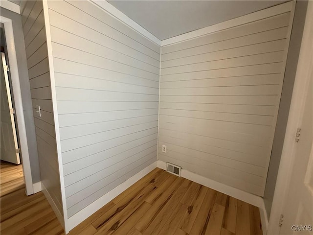 interior space with hardwood / wood-style flooring and wood walls