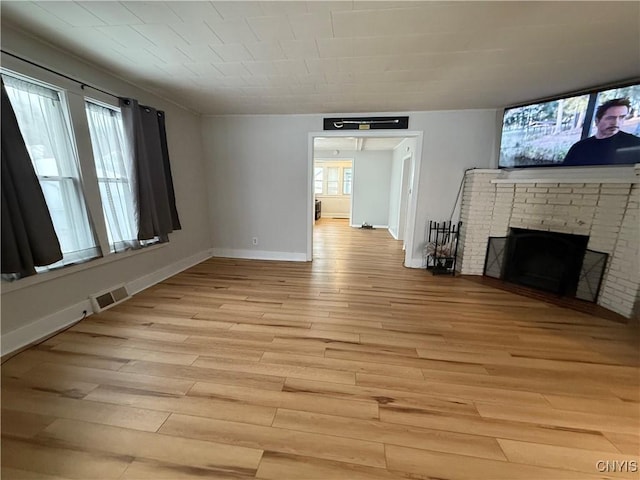 unfurnished living room featuring a fireplace and light hardwood / wood-style floors