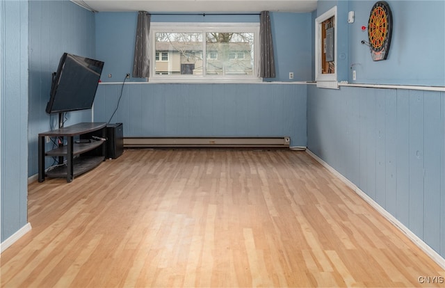 misc room with baseboard heating, wooden walls, and light hardwood / wood-style floors