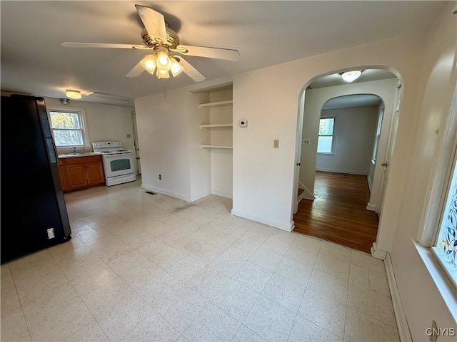 unfurnished living room with ceiling fan, light wood-type flooring, and sink