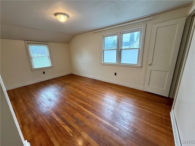 additional living space with hardwood / wood-style floors and lofted ceiling