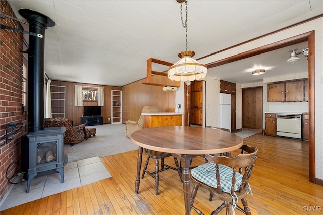 dining area featuring a wood stove, wooden walls, and light hardwood / wood-style floors