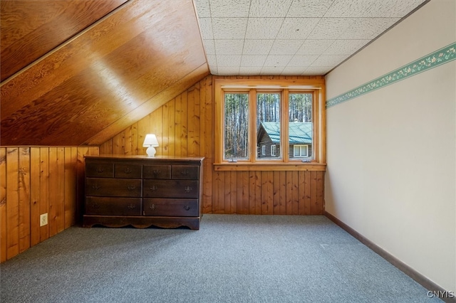 bonus room with wood walls, carpet floors, and vaulted ceiling