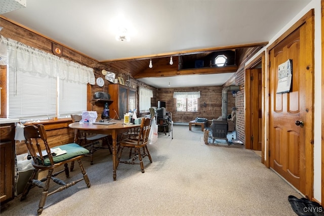 carpeted dining room with a wood stove, wooden walls, and brick wall