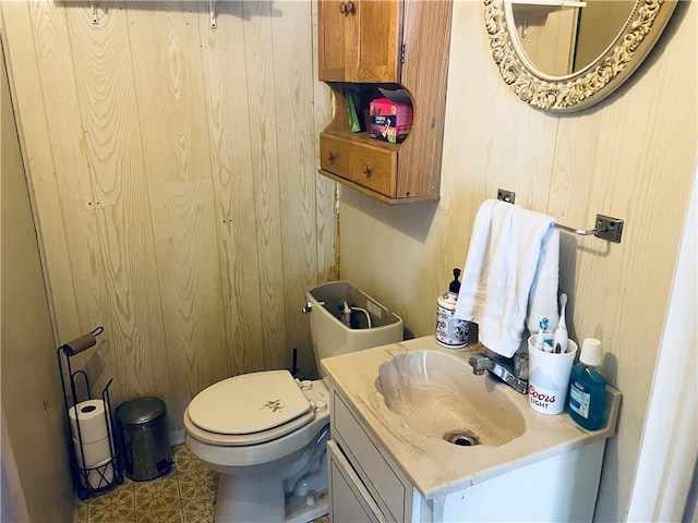 bathroom with vanity, wood walls, and toilet