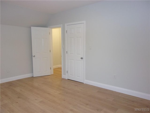 spare room featuring light hardwood / wood-style floors and vaulted ceiling