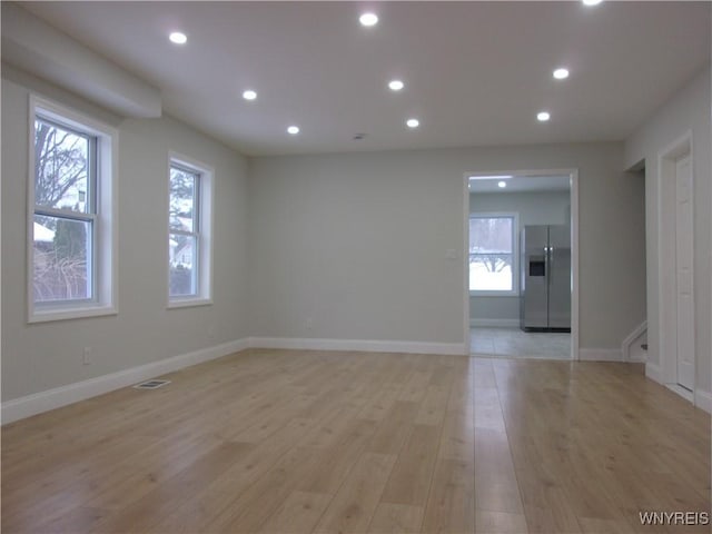 empty room with light hardwood / wood-style floors and a wealth of natural light