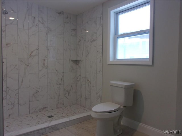 bathroom featuring a tile shower and toilet