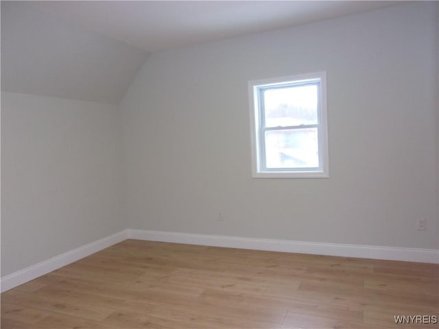 additional living space with light hardwood / wood-style floors and vaulted ceiling