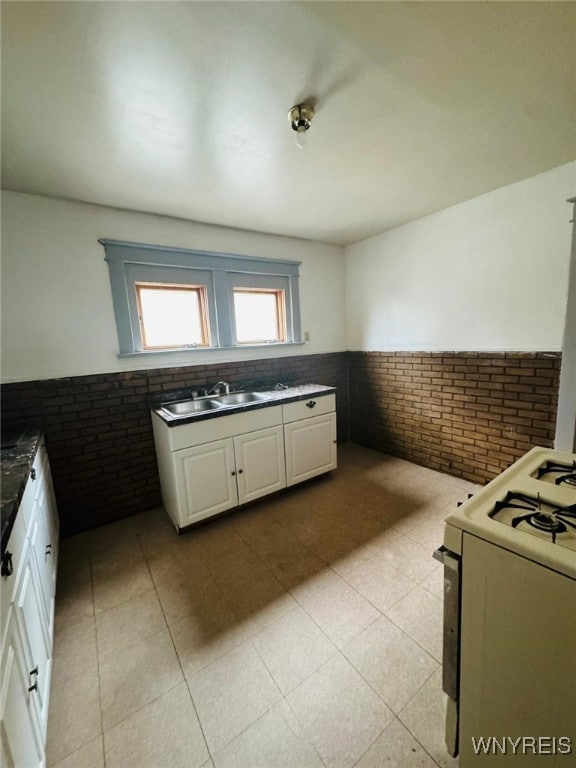 kitchen featuring white cabinets, sink, white stove, and tile walls