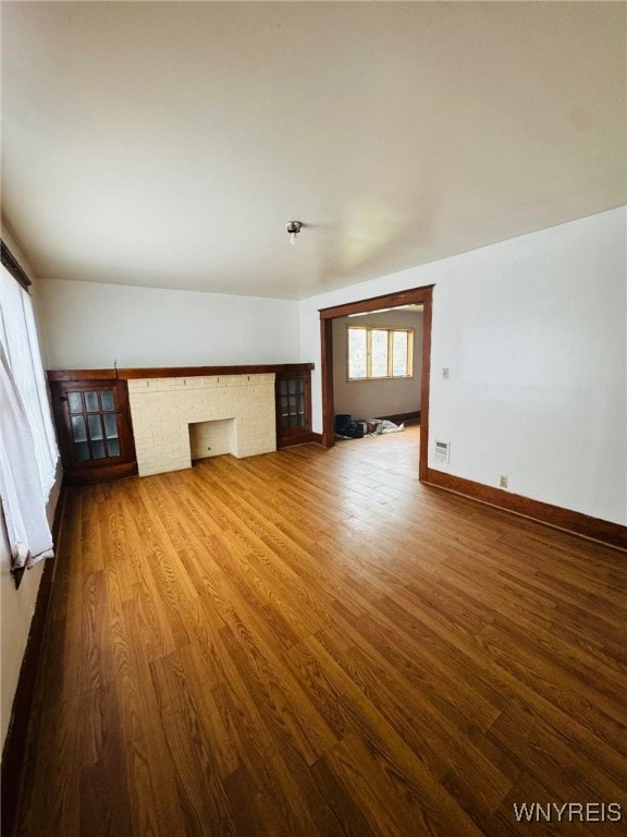 unfurnished living room with hardwood / wood-style floors and vaulted ceiling