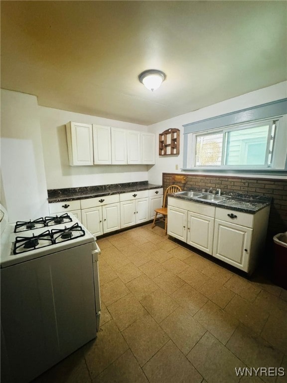 kitchen with white cabinets, range, and sink