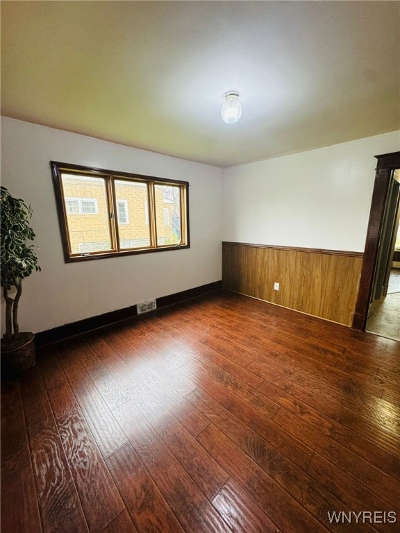 spare room featuring wood walls and dark hardwood / wood-style floors