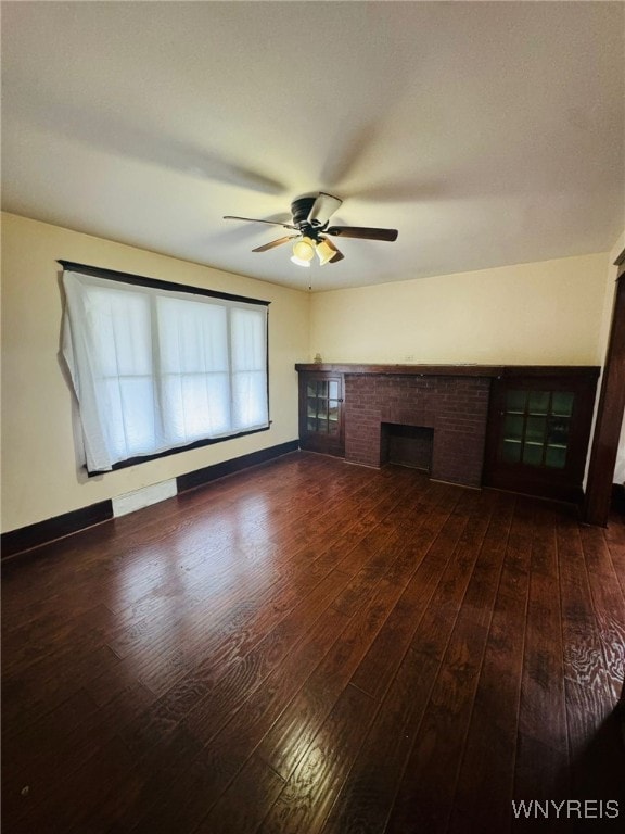 unfurnished living room with dark hardwood / wood-style floors, ceiling fan, and a brick fireplace