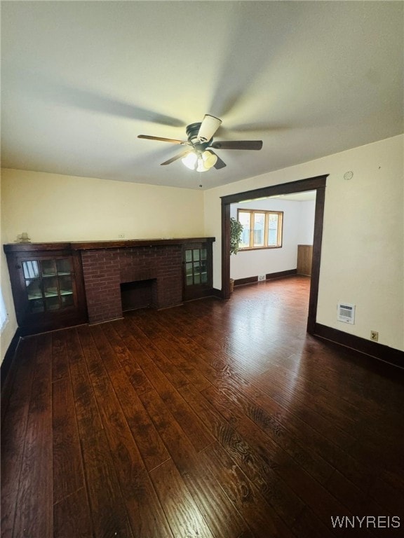 unfurnished living room featuring a fireplace, dark hardwood / wood-style flooring, and ceiling fan