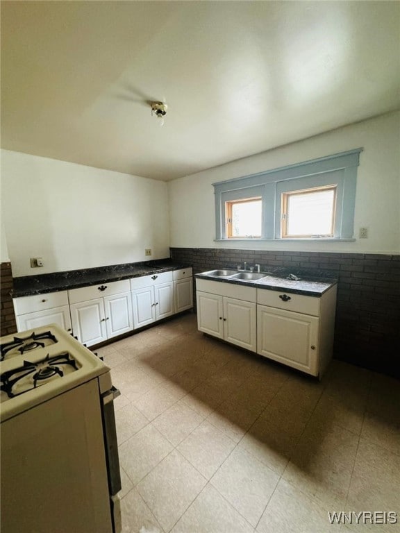 kitchen featuring white cabinets, sink, and white range with gas cooktop