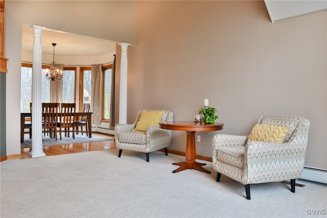 living area with light wood-type flooring, an inviting chandelier, baseboard heating, and ornate columns