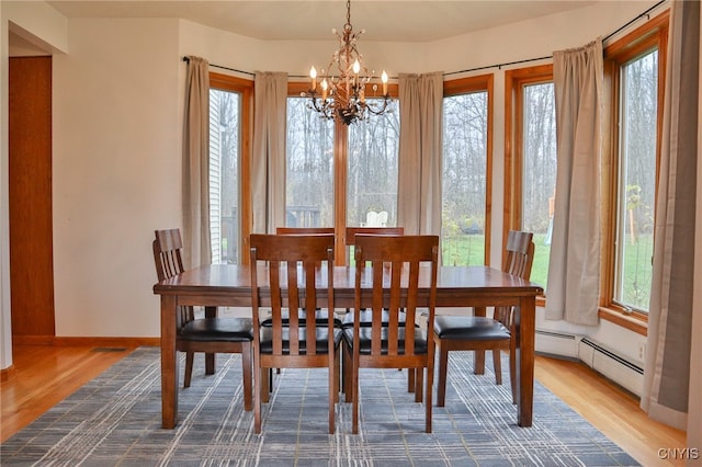 dining area featuring baseboard heating, wood-type flooring, and a notable chandelier