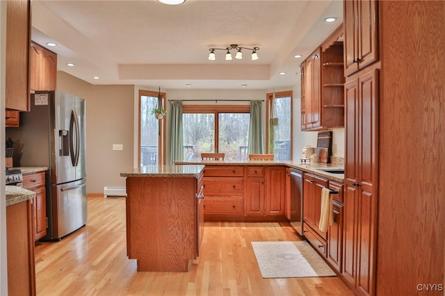 kitchen with light stone countertops, light wood-type flooring, stainless steel appliances, a baseboard radiator, and a kitchen island