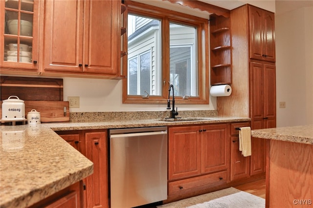 kitchen featuring dishwasher, light stone counters, light wood-type flooring, and sink