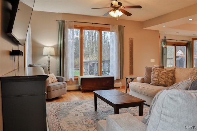 living room featuring a wealth of natural light, ceiling fan, a baseboard radiator, and light wood-type flooring