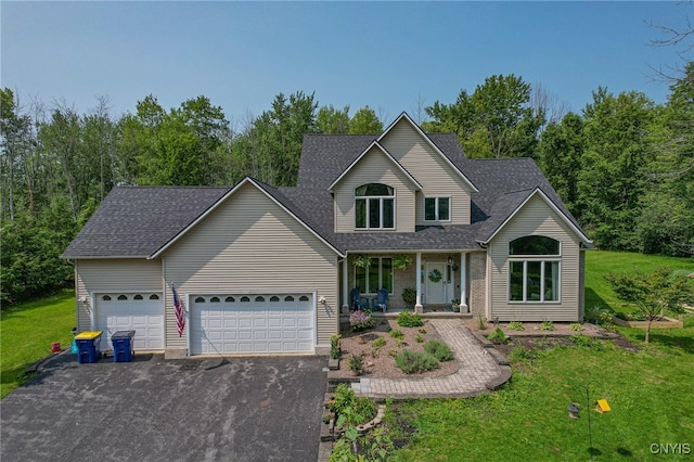 view of front property with covered porch, a front yard, and a garage