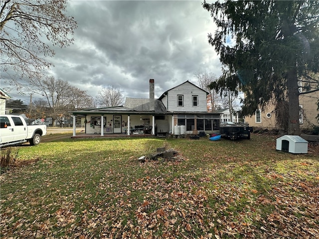 back of property with a porch and a yard