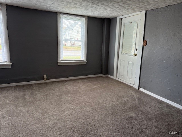 empty room with carpet floors and a textured ceiling